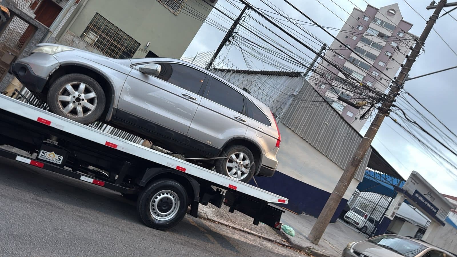Caminhão plataforma da AL Guinchos transportando um carro em São Paulo